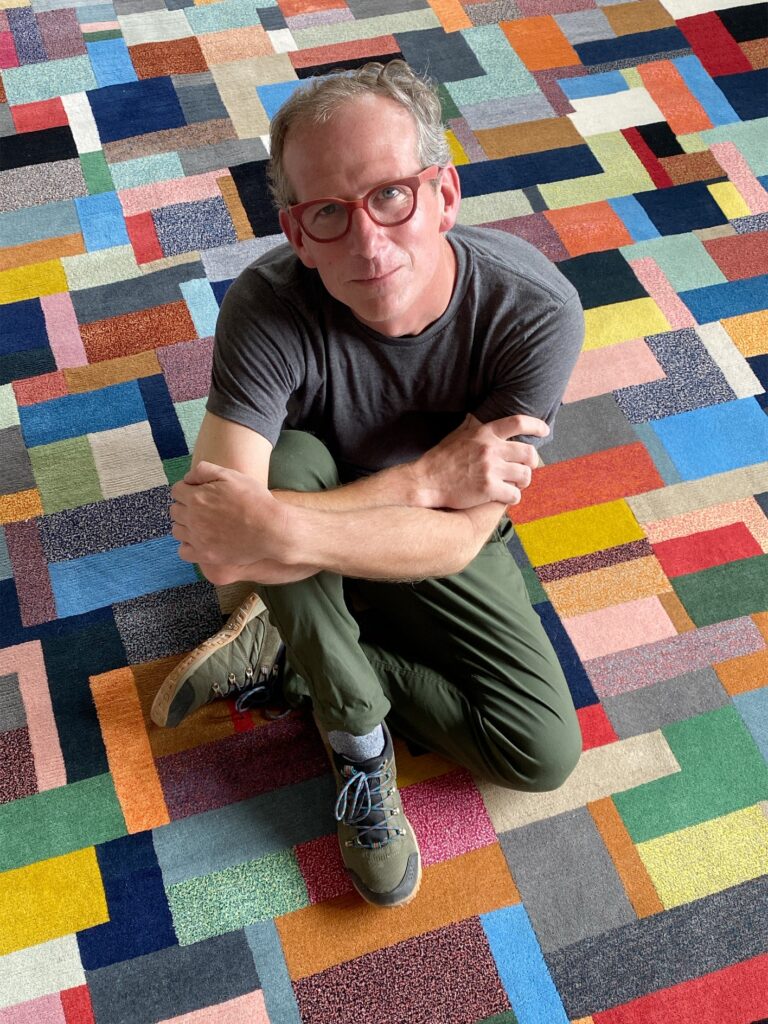 Designing Circularity: The Evolution of ECONYL® Nylon in Handmade Rugs A close-up of a man, Michael Christie, smiling and looking at the camera.