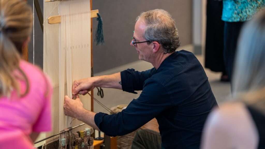 Designing Circularity: The Evolution of ECONYL® Nylon in Handmade Rugs A close-up of a man, Michael Christie, touching nylon yarn.